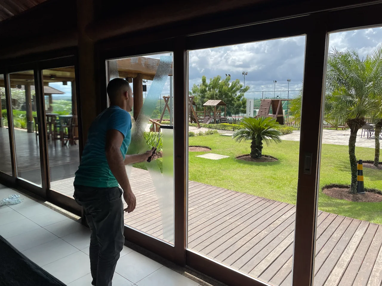 Aplicador da SOMMAR tratando porta de vidro em área de lazer residencial